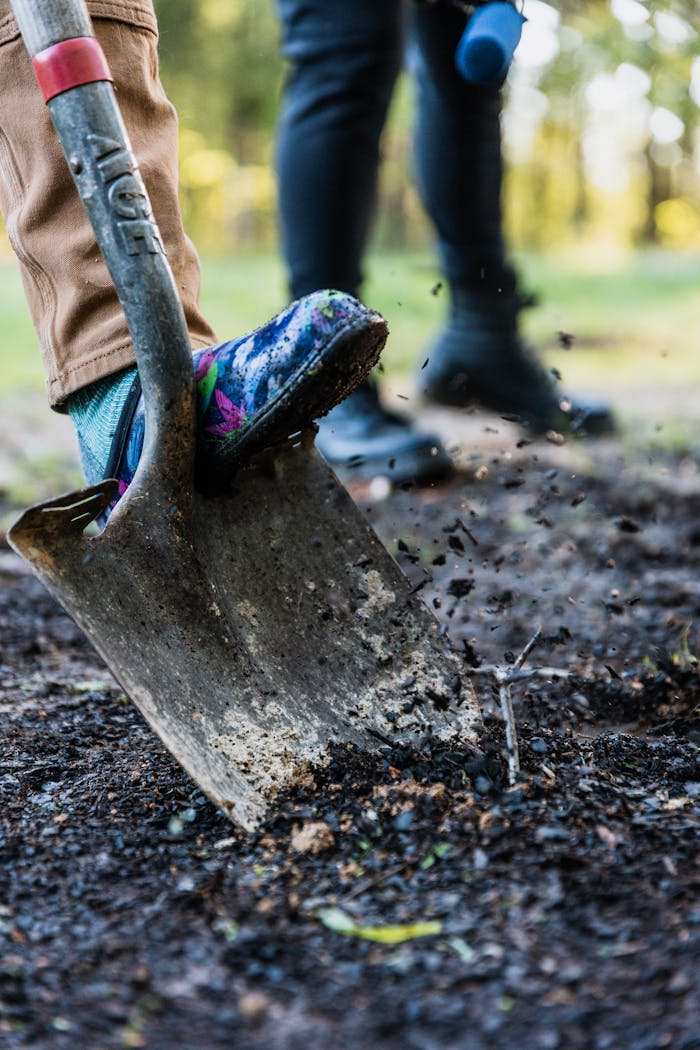 hero-img-02 Vibrant close-up of a shovel with colorful shoe digging in the soil, outdoors.